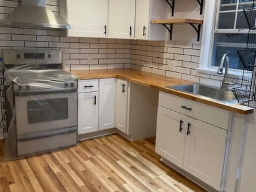 Modern kitchen with white cabinets, wooden countertops, and subway tile backsplash.